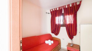 A small room with a red sofa, a wooden cabinet, and red curtains. - 5 bedroom beach front home in Arbus (Arbus)