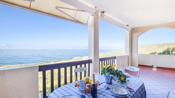 A table set for two with a view of the sea, a bottle of champagne, and a basket of fruit. - 5 bedroom beach front home in Arbus (Arbus)