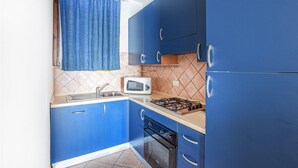 A compact kitchen with blue cabinets, a microwave, a gas stove, and an oven. - 5 bedroom beach front home in Arbus (Arbus)