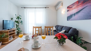 A living room with a TV, dining table with breakfast items, and a sofa.