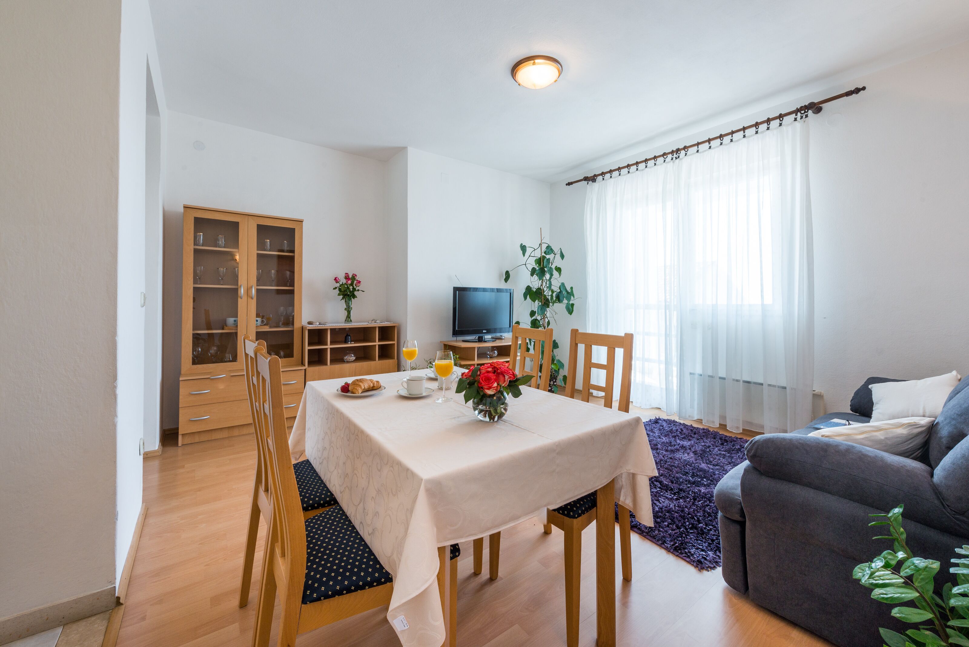 Ein Essbereich mit Tisch, Stühlen, einem Fernseher und einer Vitrine.