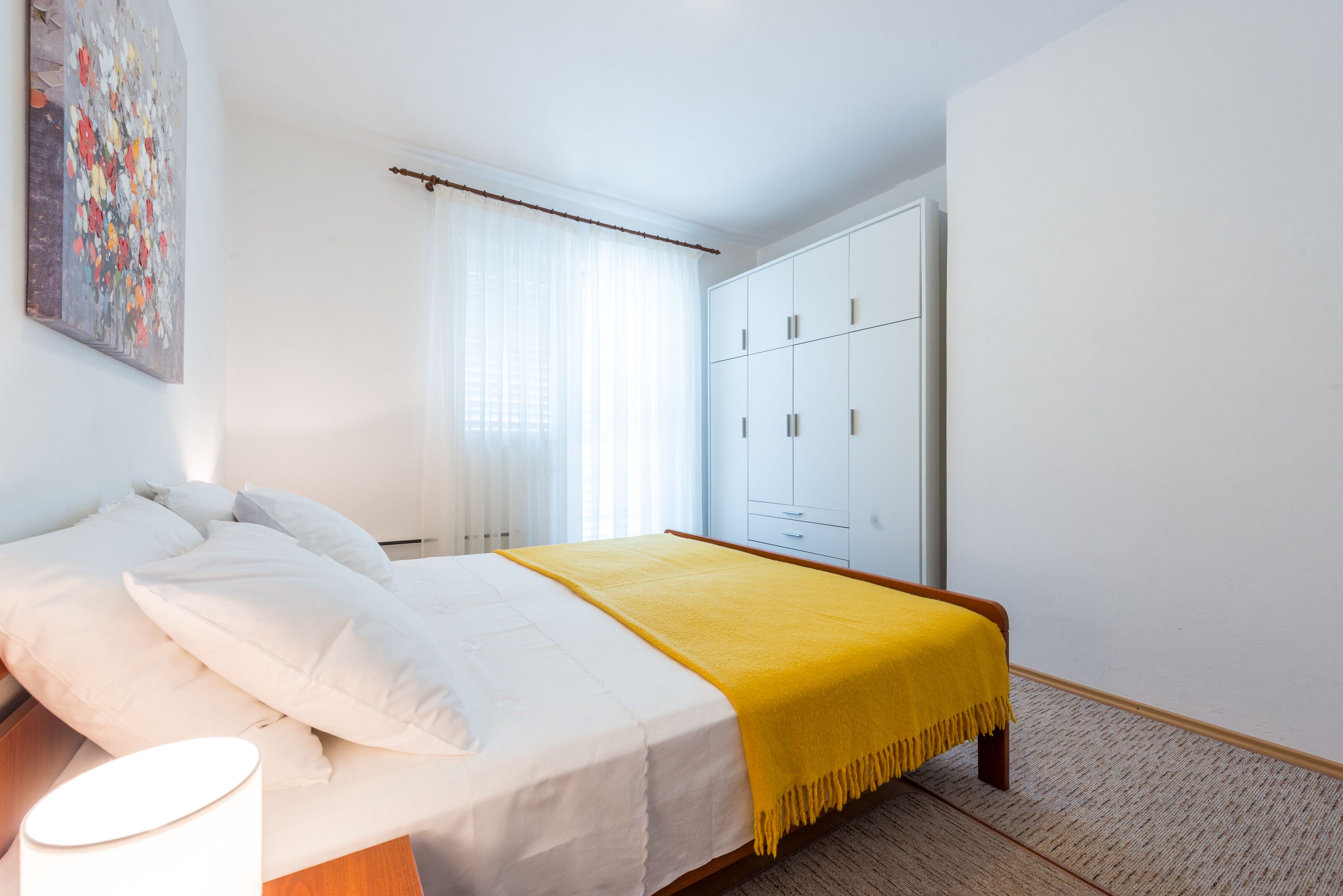 Quarto com cama, guarda-roupa e janela com cortinas.