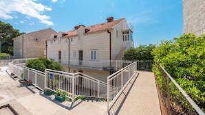 A multi-story building with a tiled roof, balconies, and a fenced courtyard with potted plants.