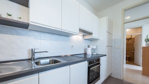 A modern kitchen with white cabinets, a stainless steel sink, and a built-in oven.