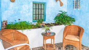 A blue-walled room with a window, a small table with a potted plant, and two wicker chairs. - Lovely home in Arenas del Rey with WiFi (Arenas del Rey)