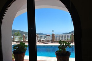 A view of a pool with a white fence and chairs, potted plants, and a mountainous landscape in the background. - Casa Biontica (Cómpeta)
