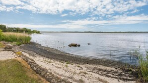 A lakeside view with a stone pathway leading to the water, surrounded by grassy areas and trees. - Lovely home in Mariager with WiFi (Mariager)