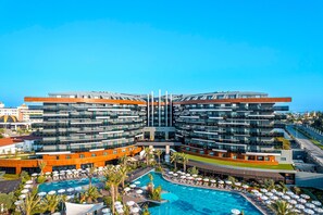 Un hotel moderno con piscina central, varios balcones y vistas despejadas del entorno.