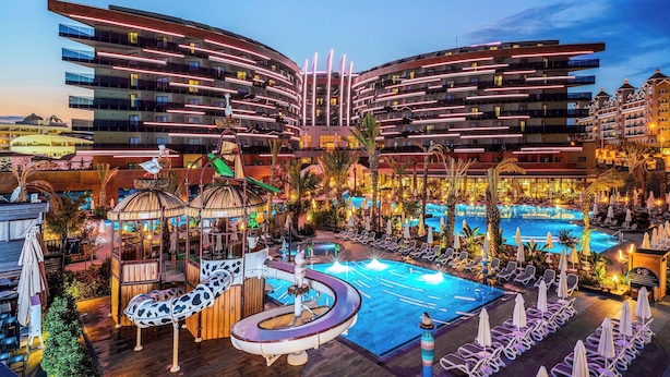 Ein modernes Hotel mit Poolbereich, inklusive Wasserrutsche und Liegestühlen.