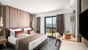 Ein modernes Hotelzimmer mit einem großen Bett, einem Schreibtisch mit Flachbildfernseher und einem Balkon mit Blick.