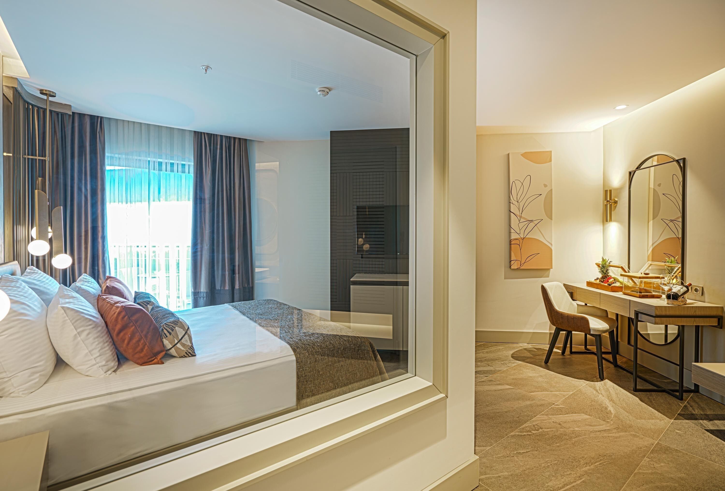 A modern hotel room with a bed, a desk, a chair, and a bathroom.