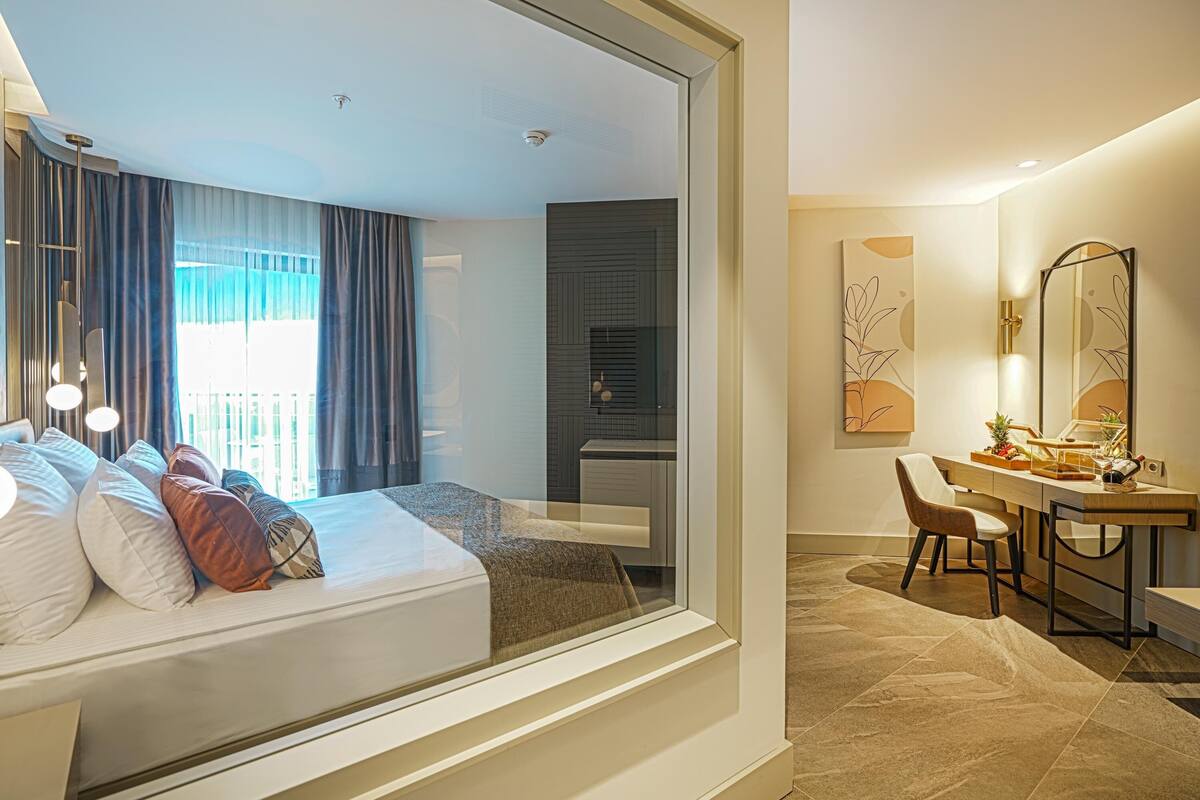 A modern hotel room with a bed, a desk, a chair, and a bathroom.