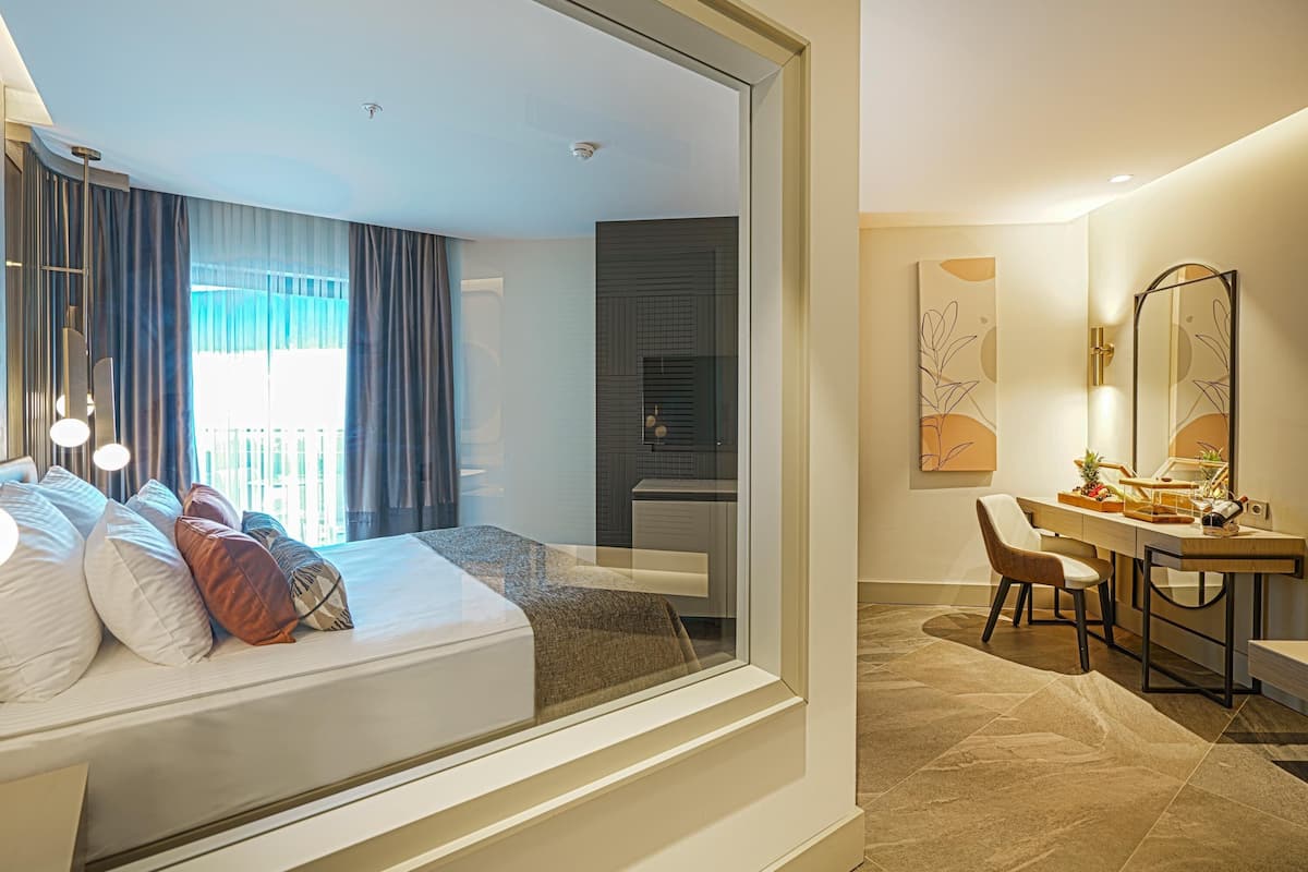 A modern hotel room with a bed, a desk, a chair, and a bathroom.