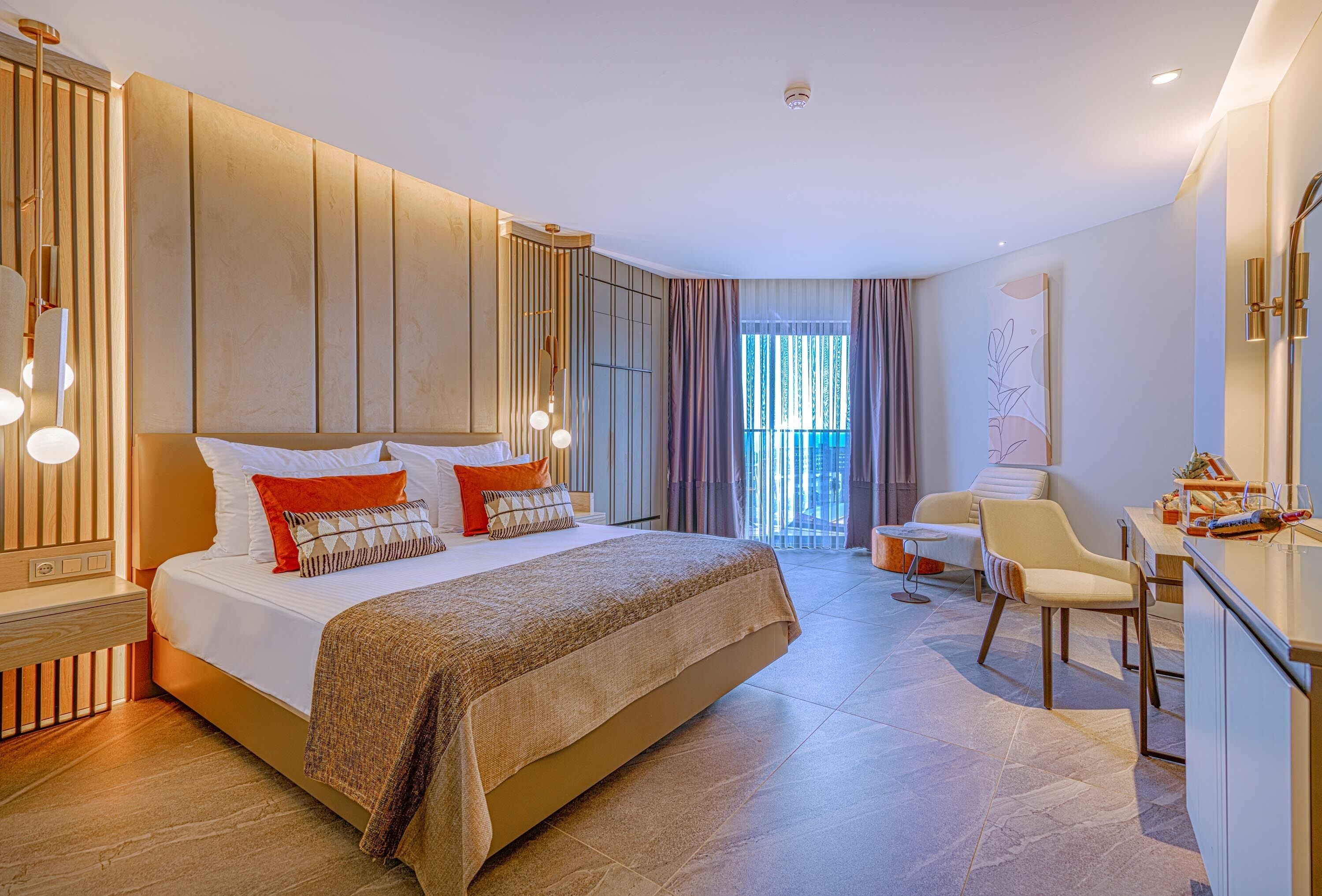 A modern hotel room with a large bed, a desk, and a view of the outdoors.