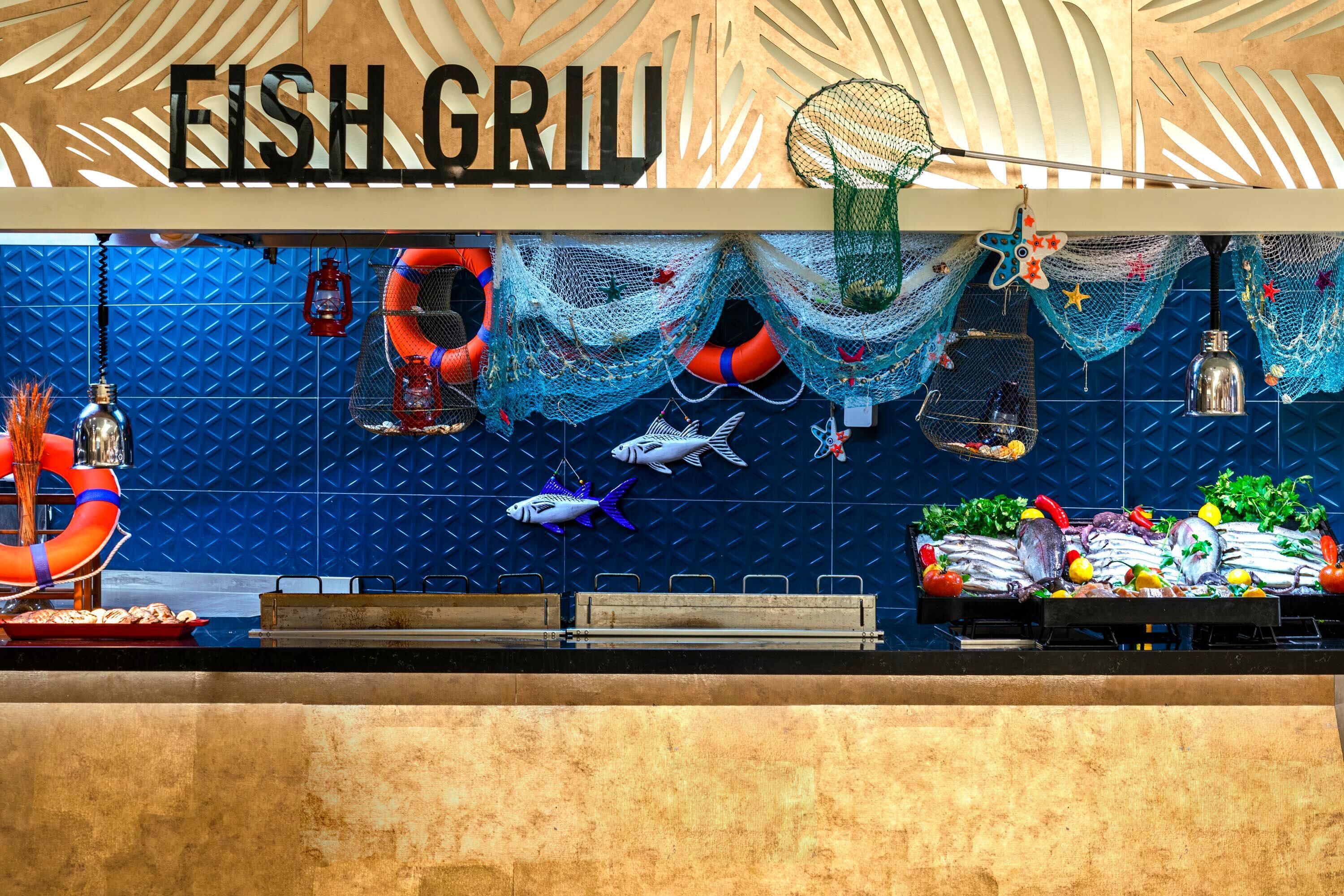 A seafood restaurant with a blue tiled wall, a fish display, and a sign that reads 'FISH GRIL'.