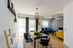 A modern living space with a dining area, a sofa, and a TV.