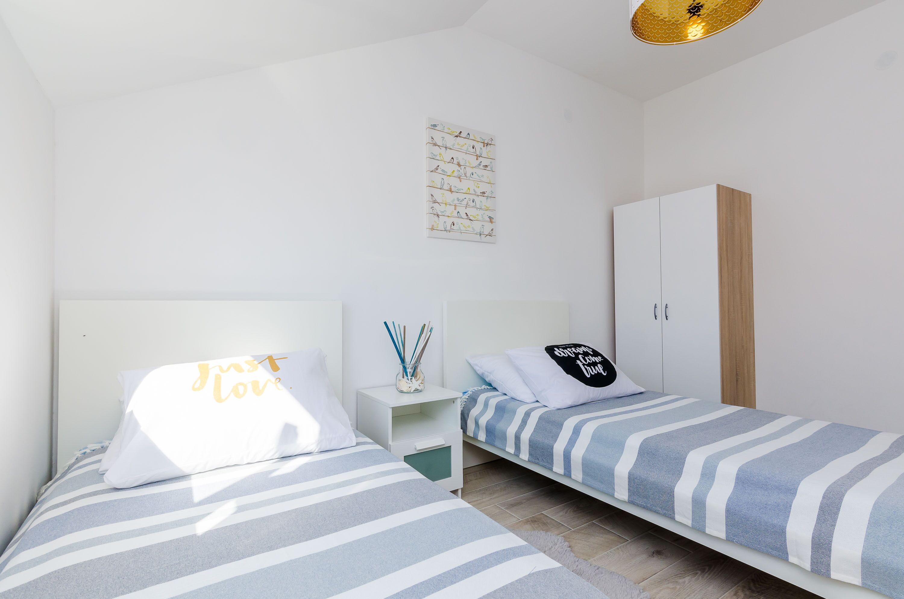 Een moderne slaapkamer met twee bedden, een witte inbouwkast en een kunstwerk aan de muur.