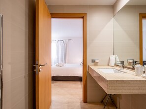 A modern bathroom with a large mirror, two sinks, and a shower area.