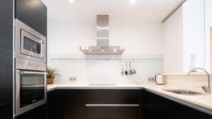 Een moderne keuken met zwarte kastjes, roestvrijstalen apparatuur en een wit aanrecht.