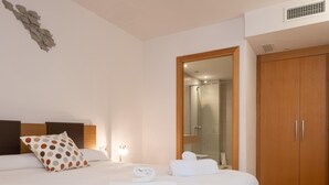 Een moderne hotelkamer met een opgemaakt bed, een houten garderobe en een douchecabine van glas.
