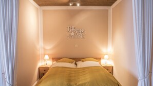 Un dormitorio con una cama, dos lámparas de noche, un cabecero con apliques de luz y una pared con una cita inspiradora.