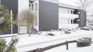 Un edificio moderno de dos pisos con techo plano, ventanas grandes y un balcón.