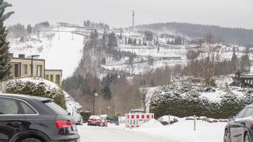 Paesaggio innevato con una seggiovia, edifici e auto parcheggiate.