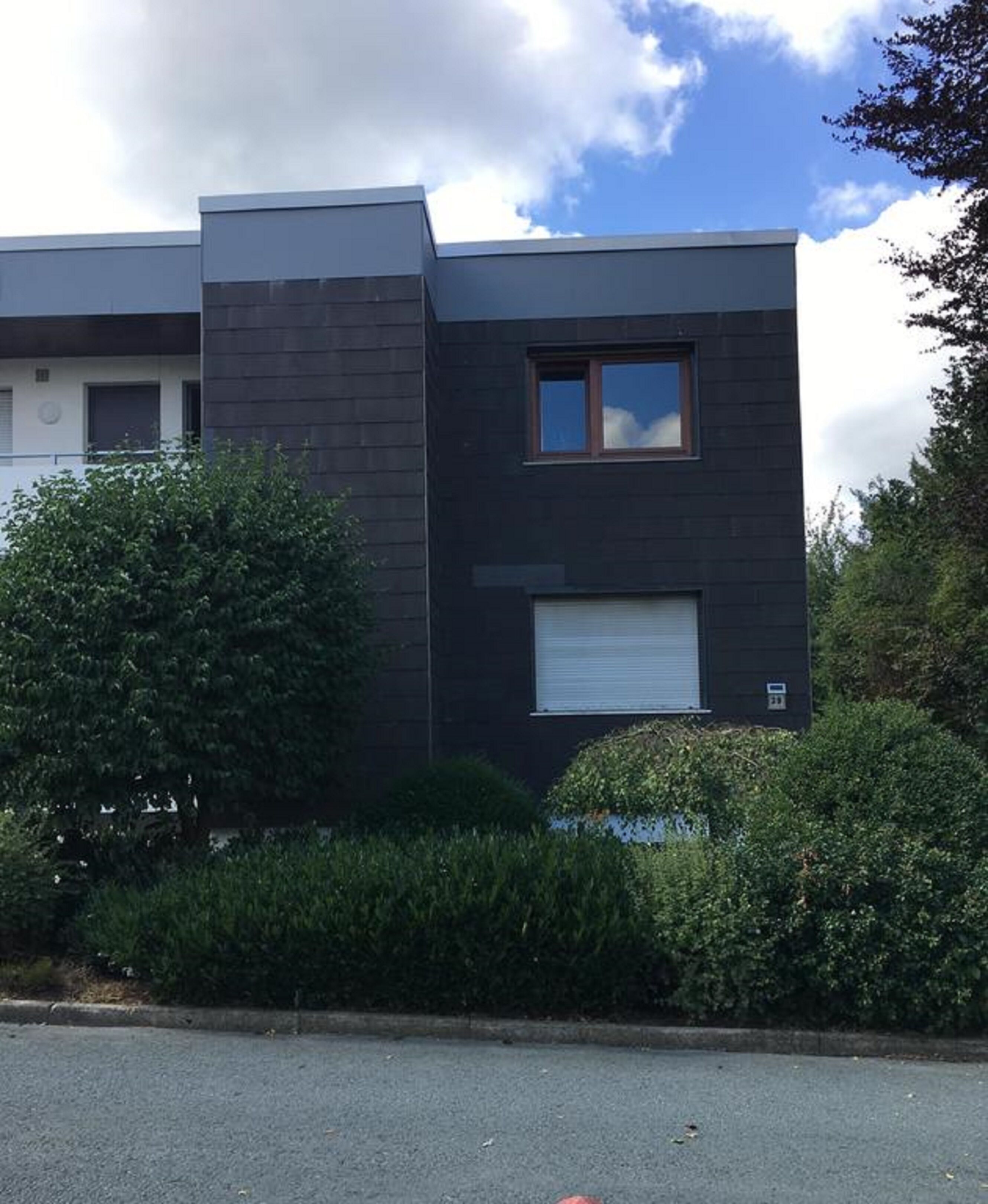 En moderne bygning med mørk facade, et lille vindue og en garageport.