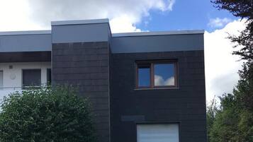 En moderne bygning med mørk facade, et lille vindue og en garageport.