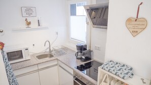 Una cocina compacta equipada con microondas, pileta, cocina y ventana.