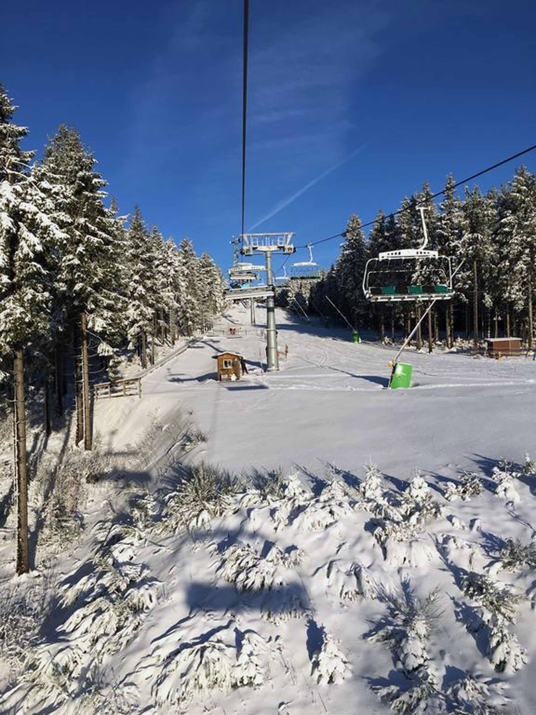 A snow-covered ski slope with a ski lift and a small wooden cabin.
