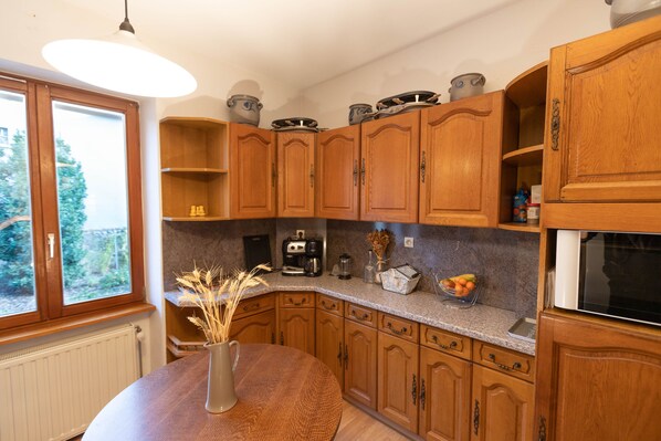 Una cocina con armarios de madera, una mesa redonda con un florero y una ventana con vista a la vegetación.