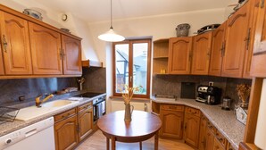 Una cocina con armarios de madera, un lavaplatos, un fregadero y una mesa de comedor con un florero.