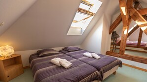 Un dormitorio con dos camas, un tragaluz, vigas de madera, una mesita de noche y una lámpara.