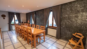 Un comedor con una gran mesa de madera y sillas, una pared negra con textura y vistas amplias con cortinas.