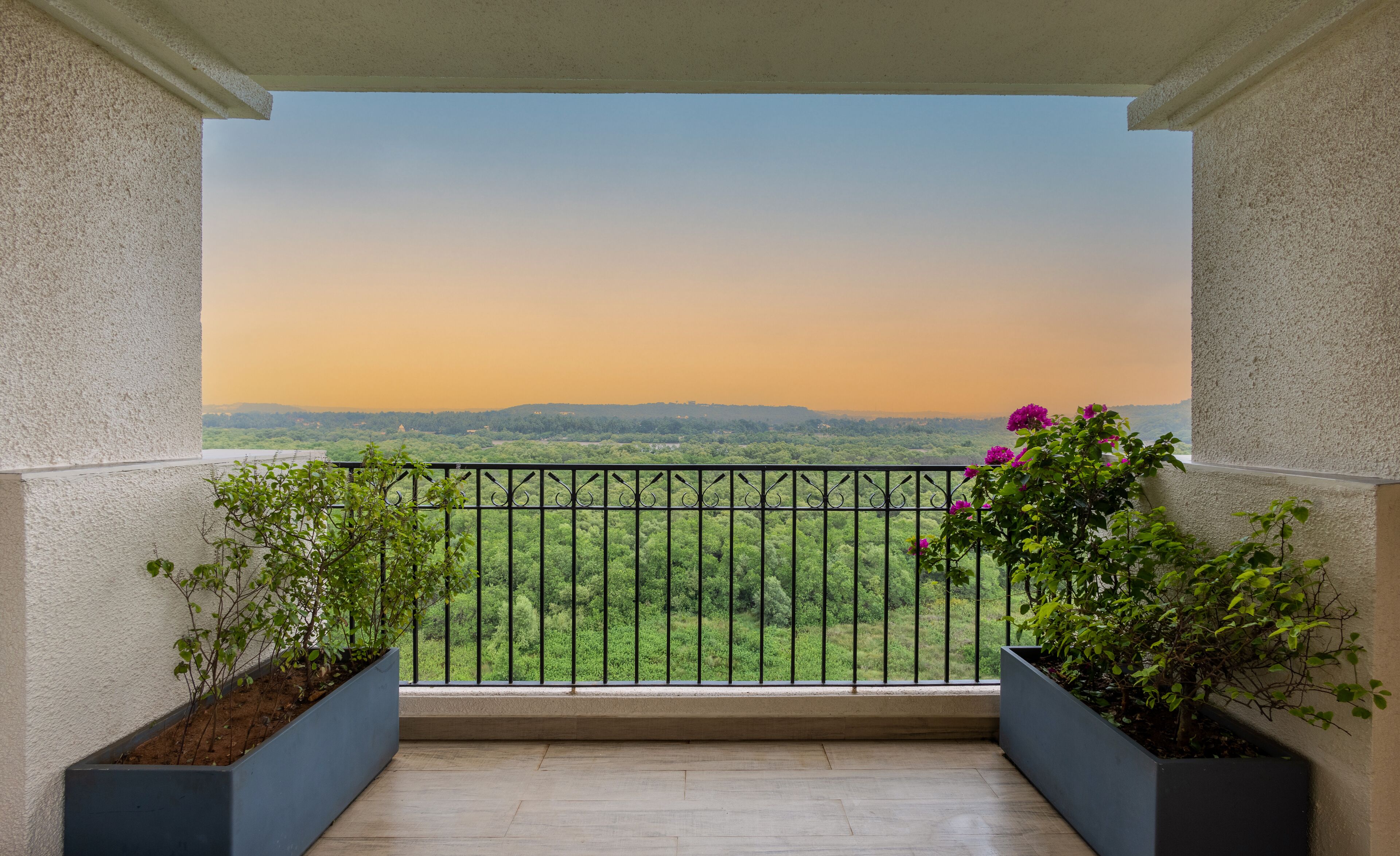 A balcony with a view of a green landscape and a sunset.