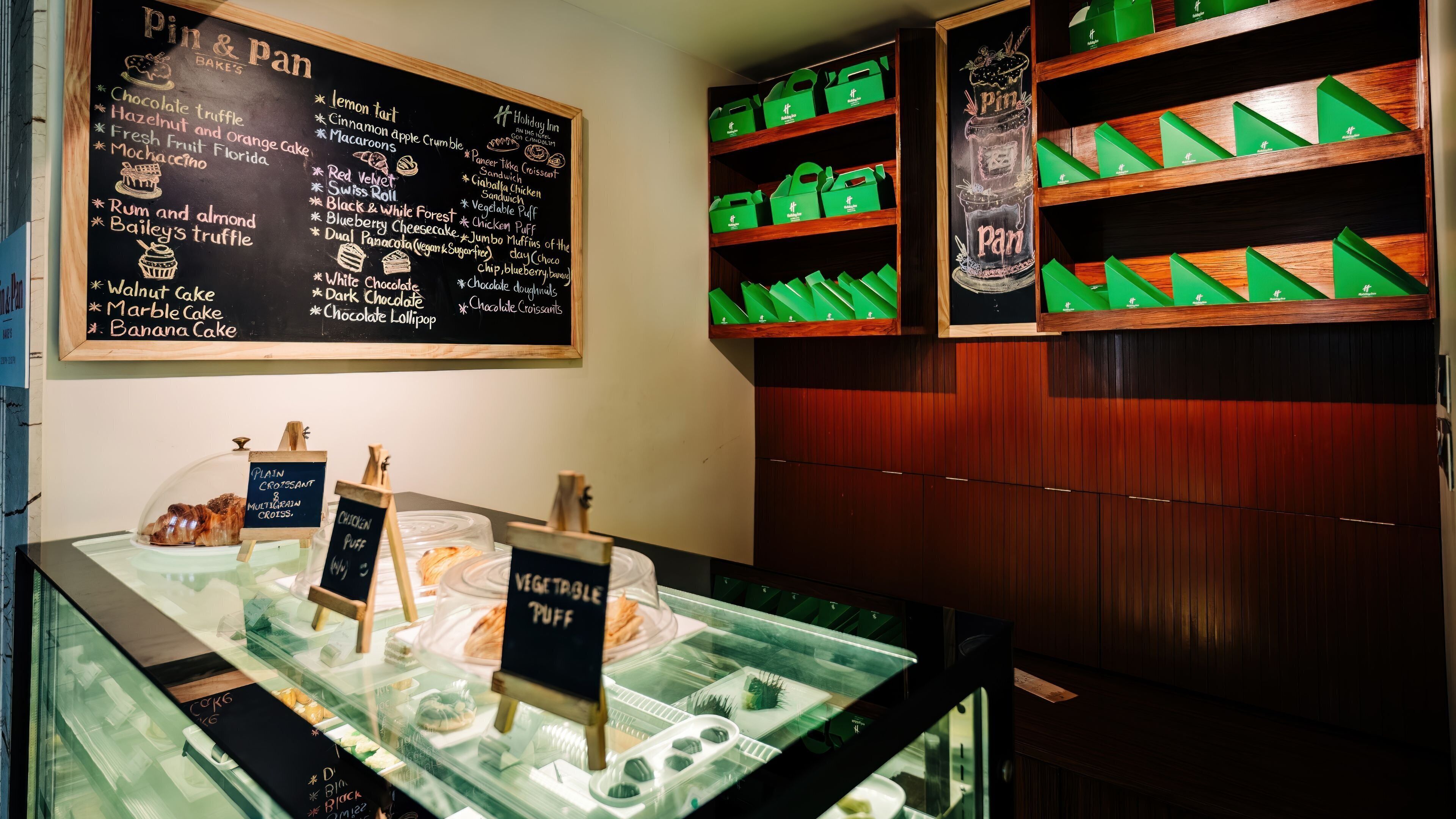 A bakery display with a chalkboard menu listing items like chocolate truffle and lemon tart.
