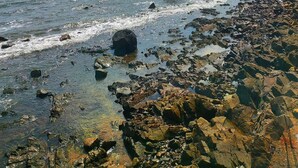 Uma costa rochosa com águas cristalinas e um céu azul vibrante.