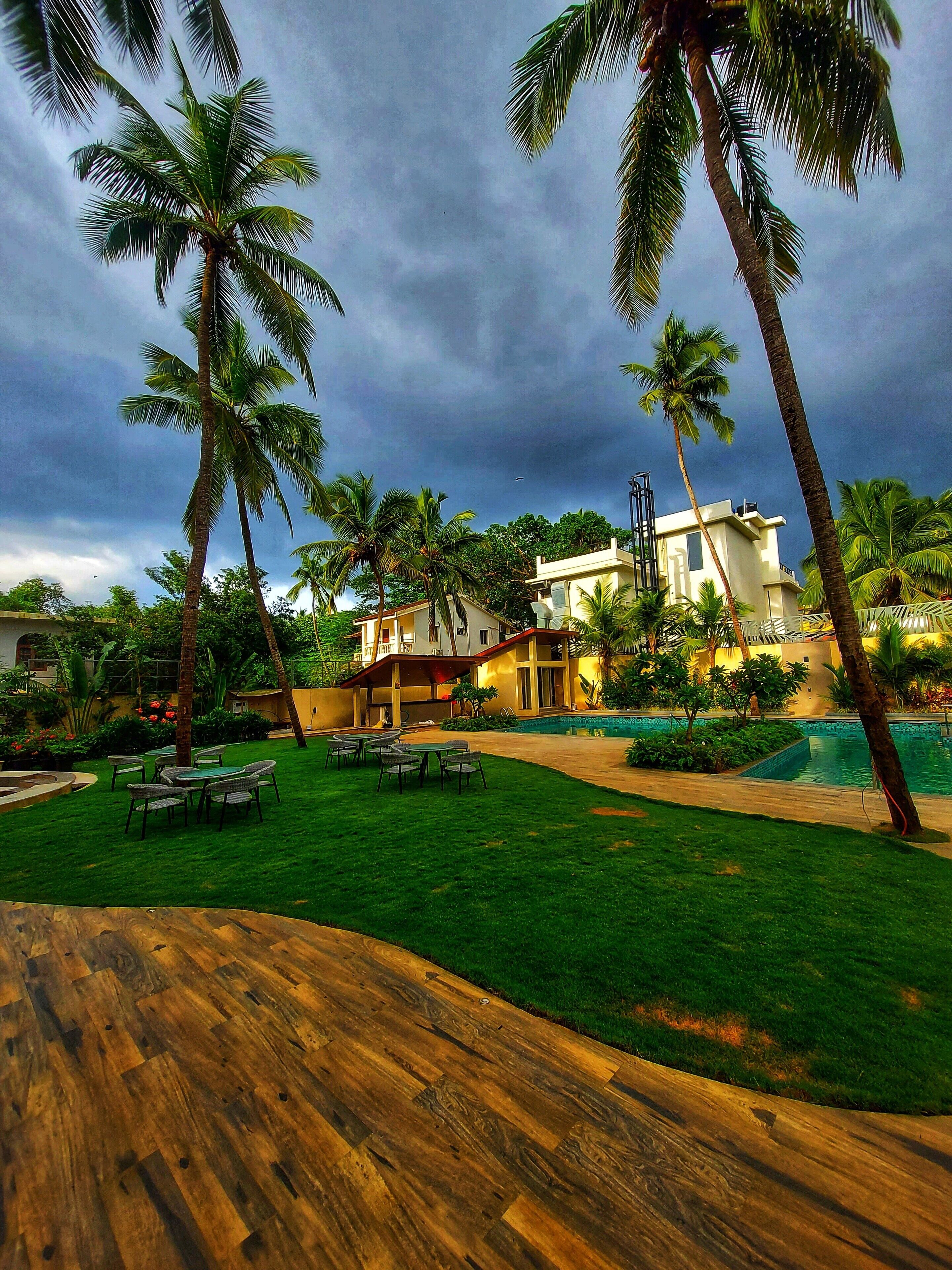 A resort with a swimming pool, palm trees, and a well-maintained lawn.