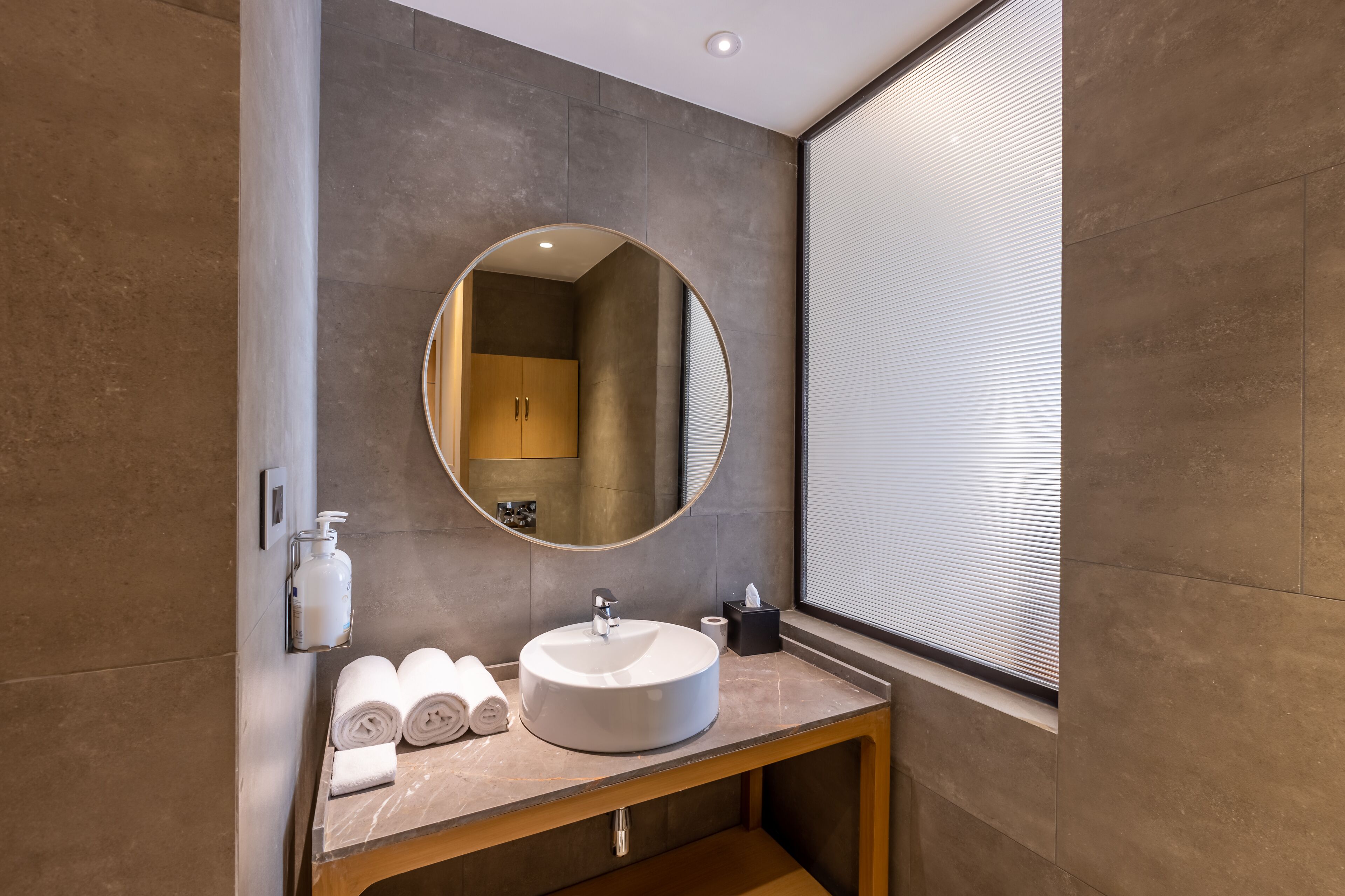 A modern bathroom with a round mirror, a sink, and a towel rack.