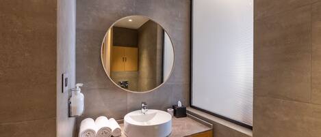 Un baño moderno con un espejo redondo, un lavamanos y un perchero para toallas.