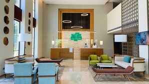 A hotel lobby with a reception desk, seating area, and large windows. - Holiday Inn Goa Candolim by IHG (Candolim)