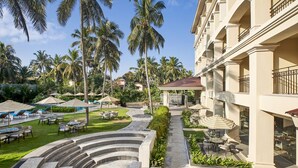 Um resort com área de piscina, mobiliário ao ar livre e palmeiras.