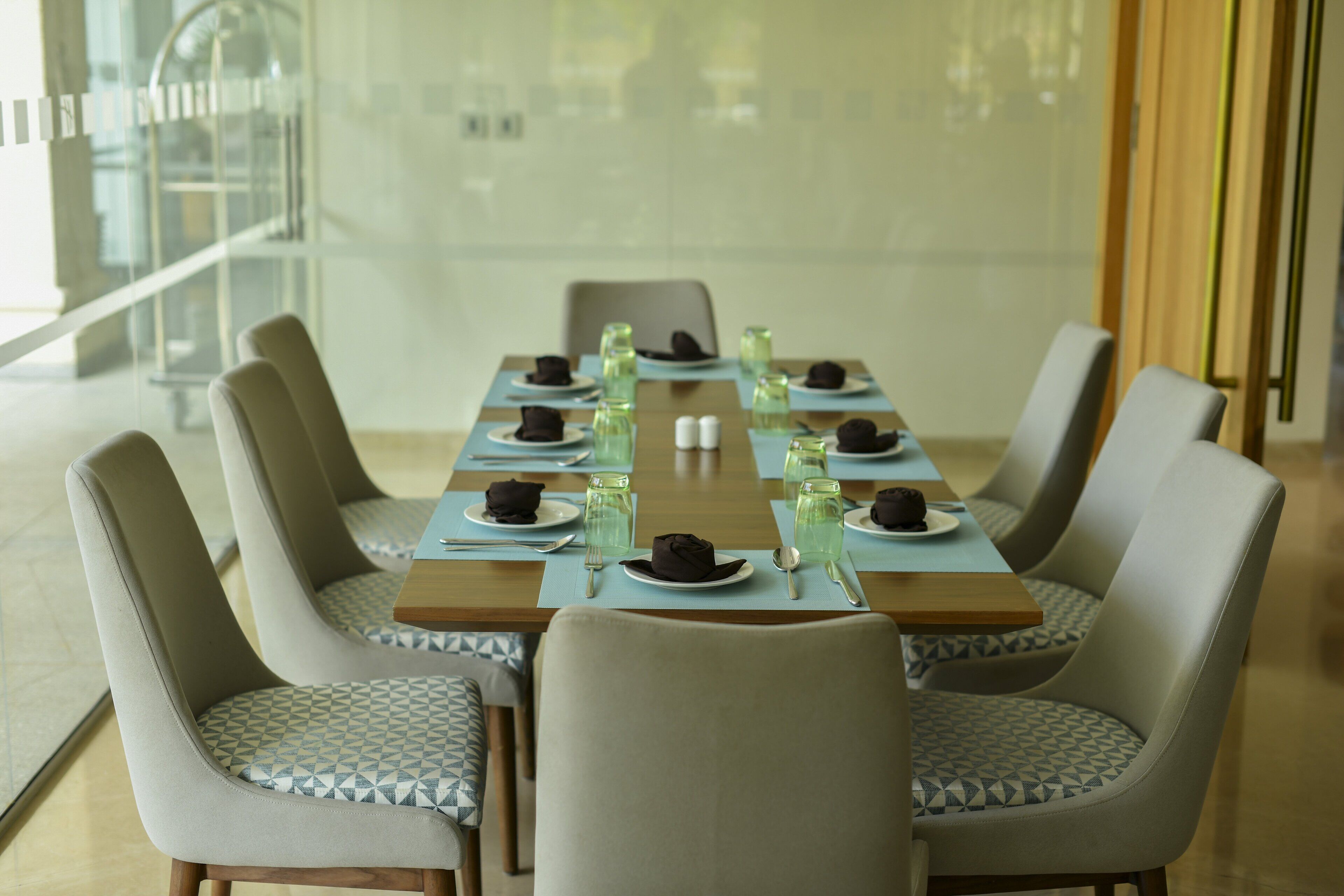 A dining area with a long table set for six, surrounded by six chairs with patterned cushions.