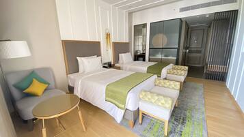 A hotel room with two beds, a sofa, a small table, and a lamp.