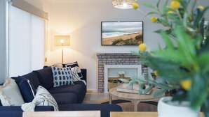Una sala de estar con un sofá, una chimenea, un televisor y una planta.