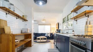 Una cocina moderna con estantes de madera, un comedor con sofá y vistas al salón.