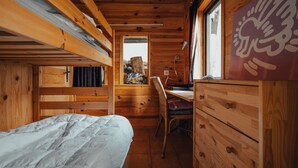 L'intérieur d'une cabane en bois, avec un lit superposé, un bureau et une chaise.