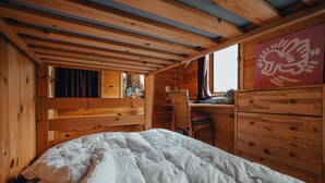 Une chambre dans une cabane en bois, avec un lit, un bureau et une commode.