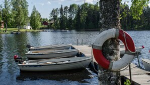 Un muelle con tres botes y un flotador atado a un árbol.